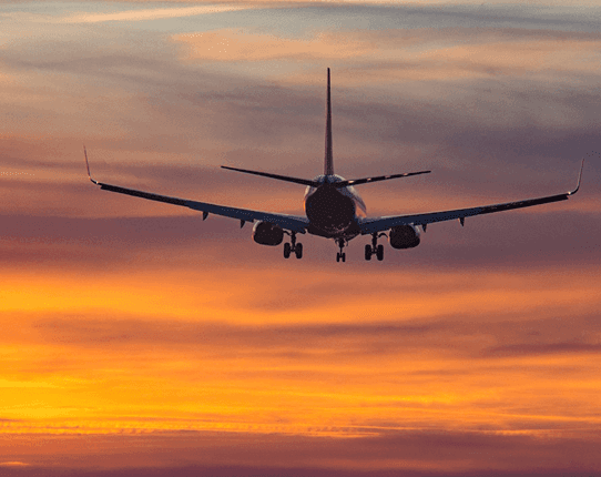 Airplane flying towards sunset